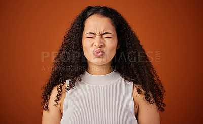 Buy stock photo Cropped shot of an attractive young woman making a face in studio against a red background
