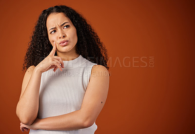 Buy stock photo Cropped shot of an attractive young woman looking thoughtful in studio against a red background