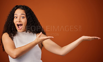 Buy stock photo Cropped portrait of an attractive young woman presenting copyspace in studio against a red background