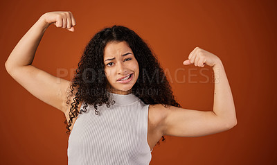 Buy stock photo Cropped portrait of an attractive young woman flexing her biceps in studio against a red background