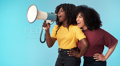 Buy stock photo Studio shot of two young women using a megaphone against a blue background