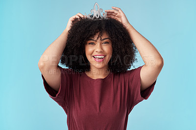 Buy stock photo Studio shot of a young woman putting a crown her head against a blue background