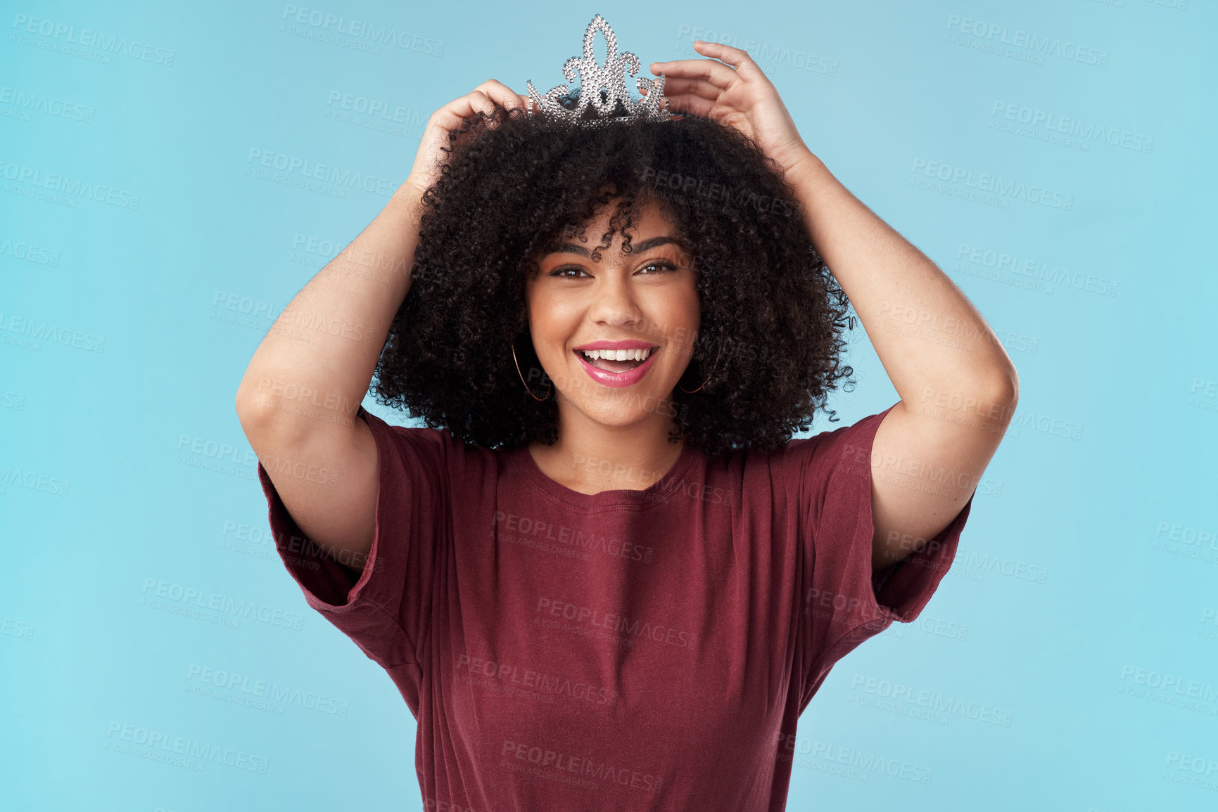 Buy stock photo Studio shot of a young woman putting a crown her head against a blue background