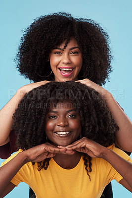 Buy stock photo Studio shot of two young women standing together against a blue background