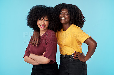 Buy stock photo Studio shot of two young women embracing each other against a blue background