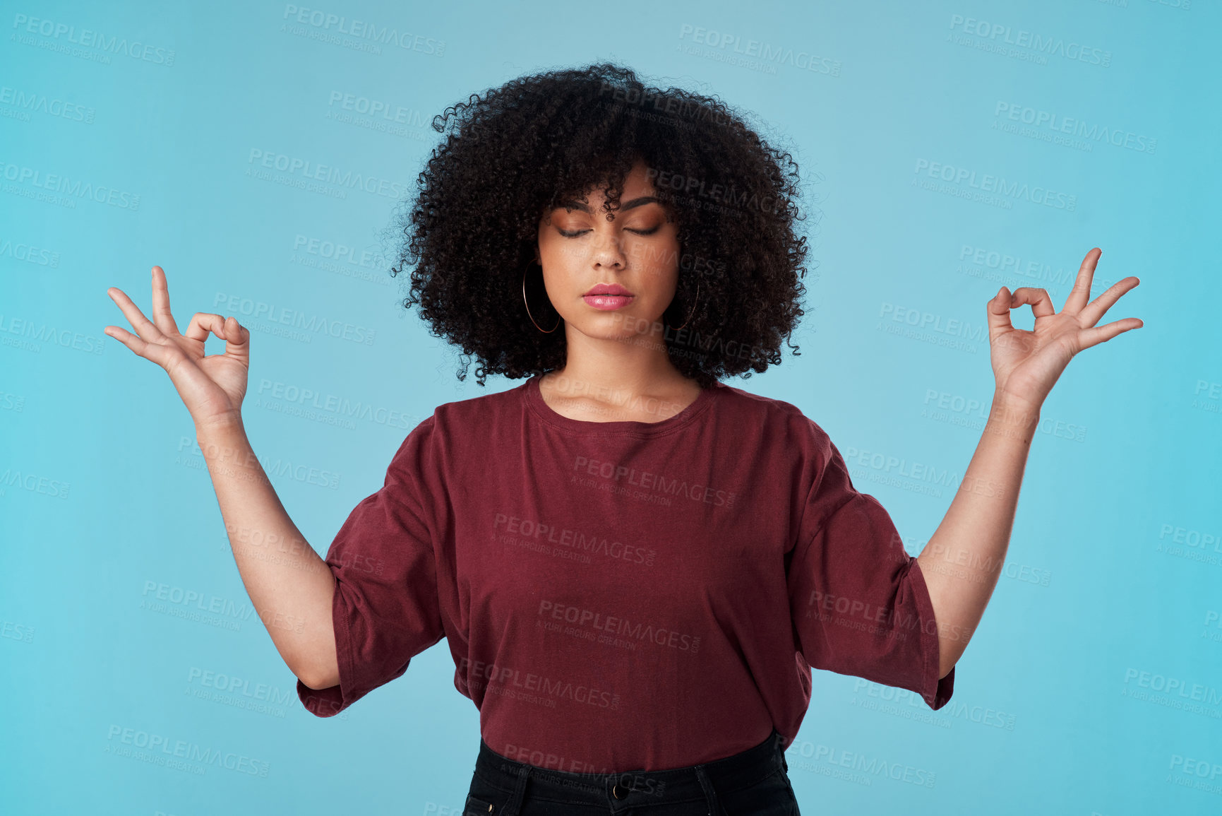 Buy stock photo Studio shot of an attractive young woman meditating against a blue background