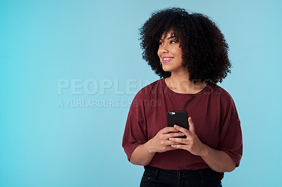 Buy stock photo Studio shot of a young woman using a smartphone against a blue background