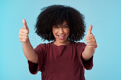 Buy stock photo Studio shot of a young woman showing thumbs up against a blue background