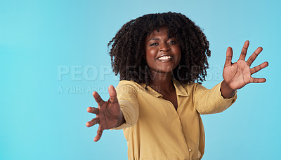 Buy stock photo Studio shot of an attractive young woman extending her arms against a blue background