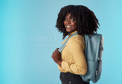 Buy stock photo Studio shot of an attractive young woman carrying a backpack against a blue background