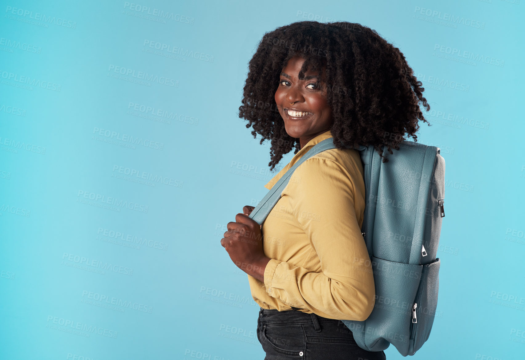 Buy stock photo Studio shot of an attractive young woman carrying a backpack against a blue background