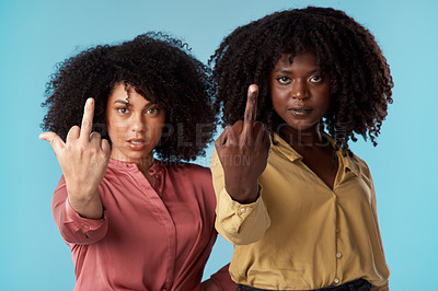Buy stock photo Studio shot of two young women showing their middle fingers against a blue background