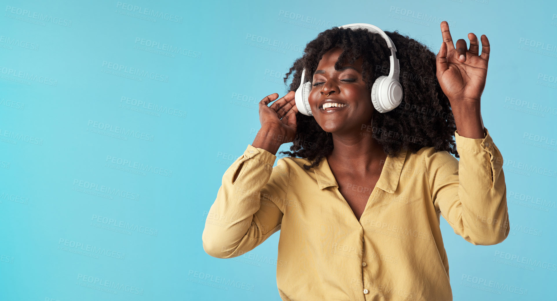 Buy stock photo Studio shot of a young woman using headphones and dancing against a blue background