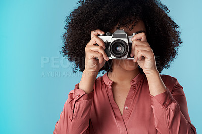 Buy stock photo Studio shot of a young woman using a camera against a blue background