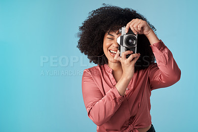 Buy stock photo Studio shot of a young woman using a camera against a blue background