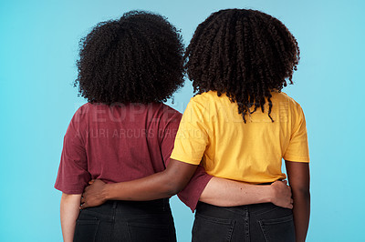 Buy stock photo Studio shot of two young women embracing each other against a blue background