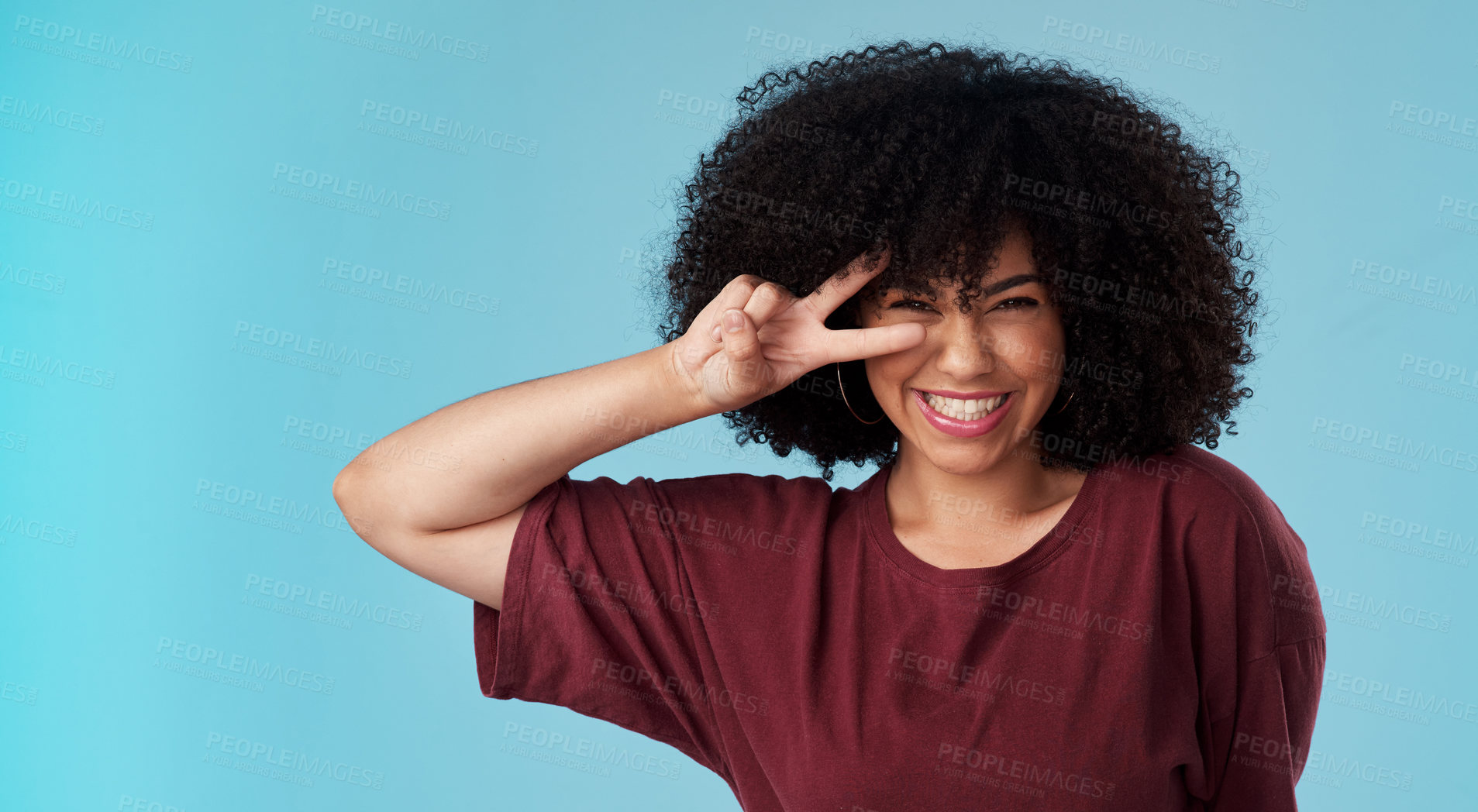 Buy stock photo Studio shot of an attractive young woman making a peace gesture against a blue background