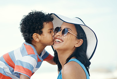 Buy stock photo Shot of a young mother receiving a kiss on the cheek from her son at the beach