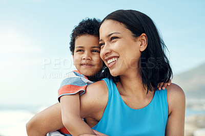 Buy stock photo Shot of a mom carrying her son on her back while enjoying a beach vacation