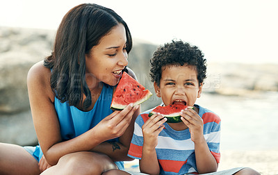 Buy stock photo Shot of a mother and sitting down and enjoying some watermelon at the beach