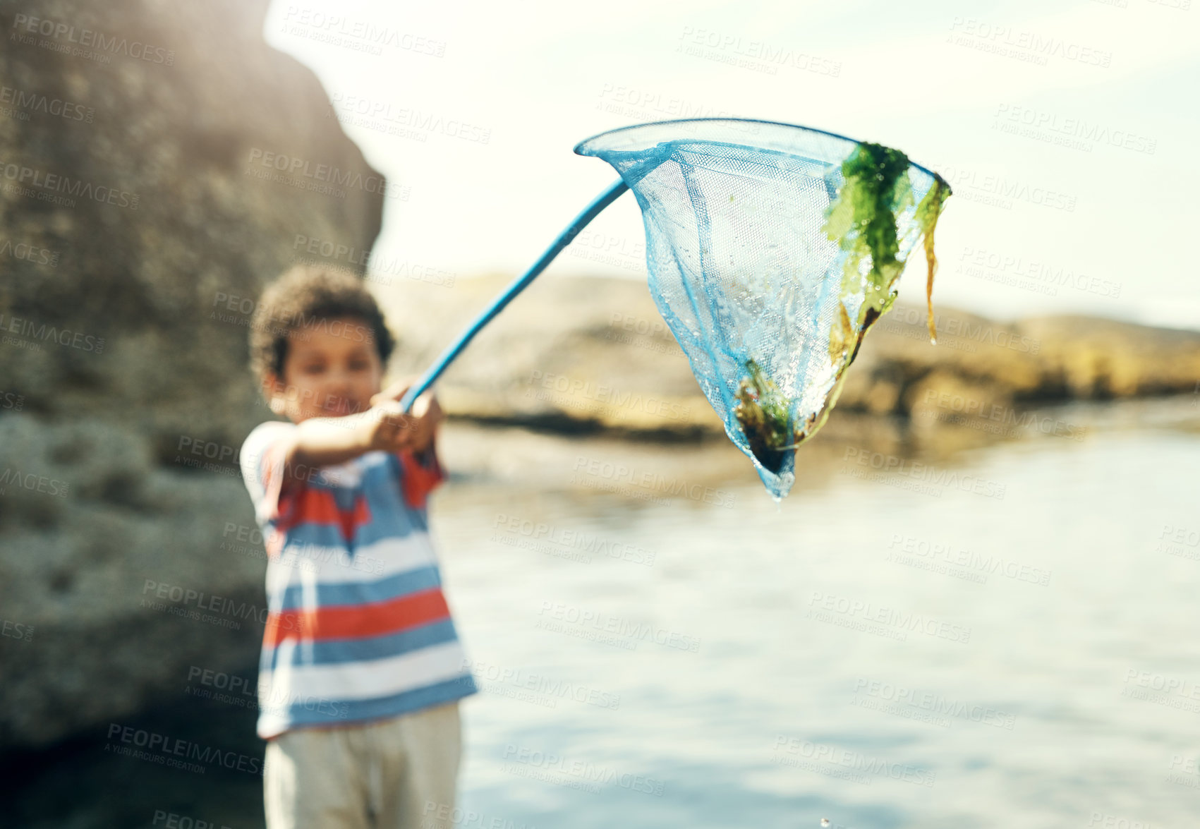 Buy stock photo Shot of a young boy holding a fishing net at the beach