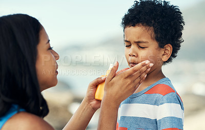 Buy stock photo Shot of a mother applying sunscreen to her son at the beach
