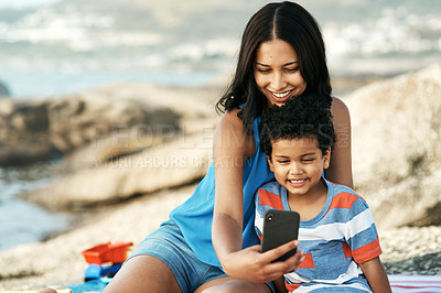 Buy stock photo Shot of a mother and her son taking selfies at the beach