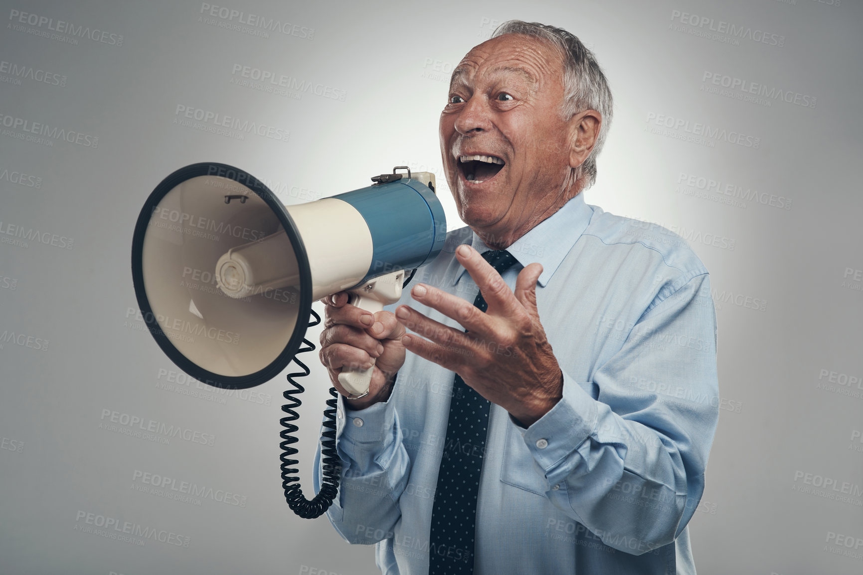 Buy stock photo Shot of a senior businessman standing alone against a grey background in the studio and using a megaphone