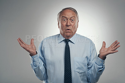 Buy stock photo Shot of a senior businessman standing alone against a grey background in the studio and looking confused