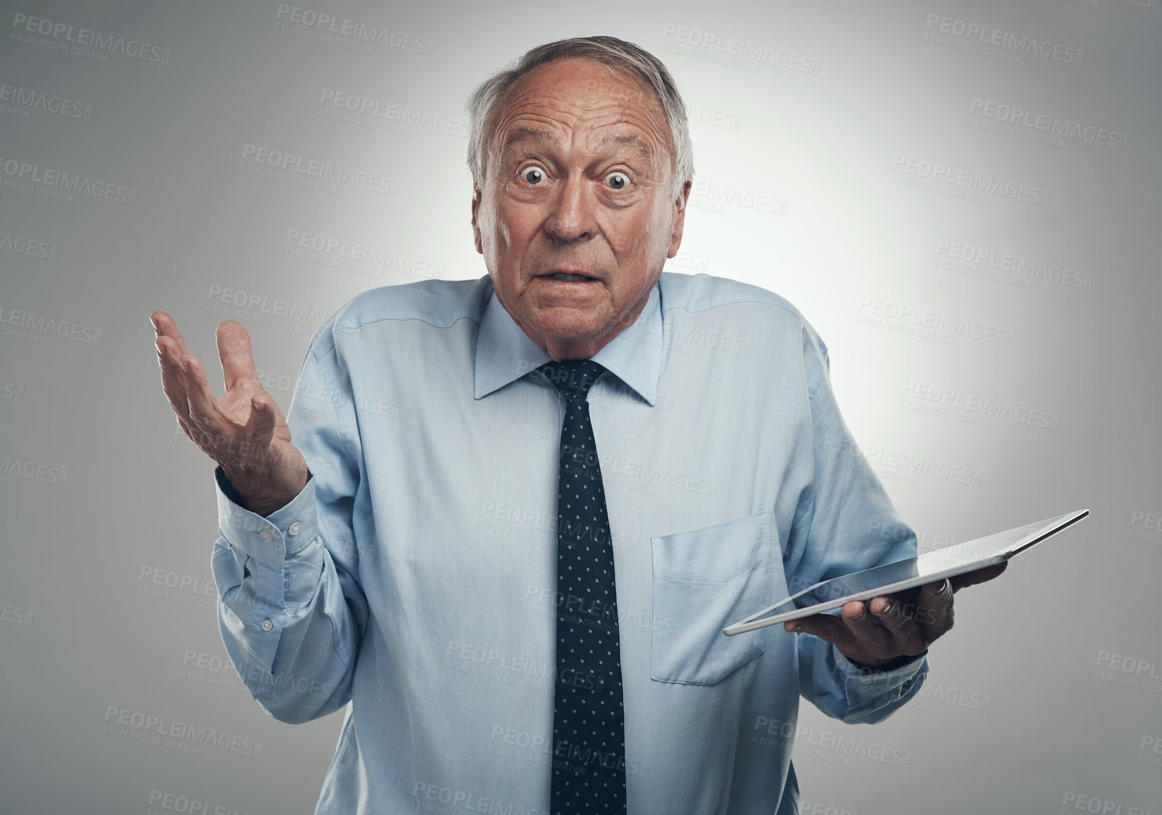 Buy stock photo Shot of a senior businessman standing alone against a grey studio background and looking confused while holding a digital tablet