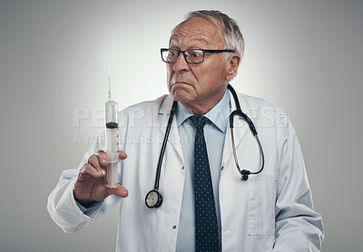 Buy stock photo Shot of an elderly male doctor holding a syringe for injection in a studio against a grey background