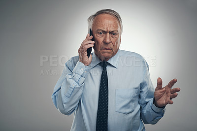 Buy stock photo Shot of a senior businessman standing against a grey background in the studio and looking confused while using his cellphone