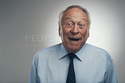 Buy stock photo Shot of a senior businessman standing alone against a grey background in the studio and pulling a silly face
