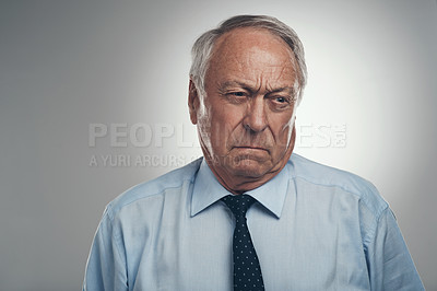 Buy stock photo Shot of a senior businessman standing alone against a grey background in the studio and looking annoyed