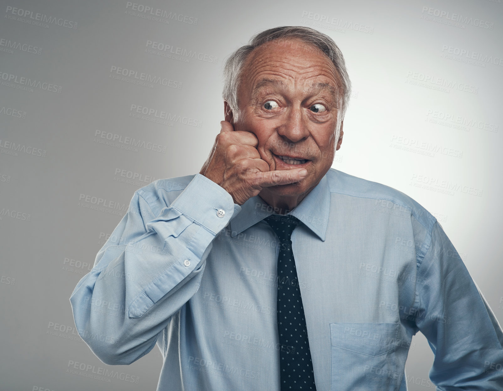 Buy stock photo Shot of a senior businessman standing alone against a grey studio background and making a cellphone hand gesture