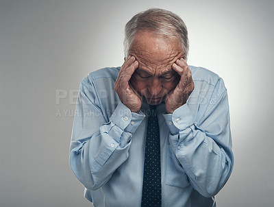 Buy stock photo Shot of a senior businessman standing alone against a grey background in the studio with his head in his hands