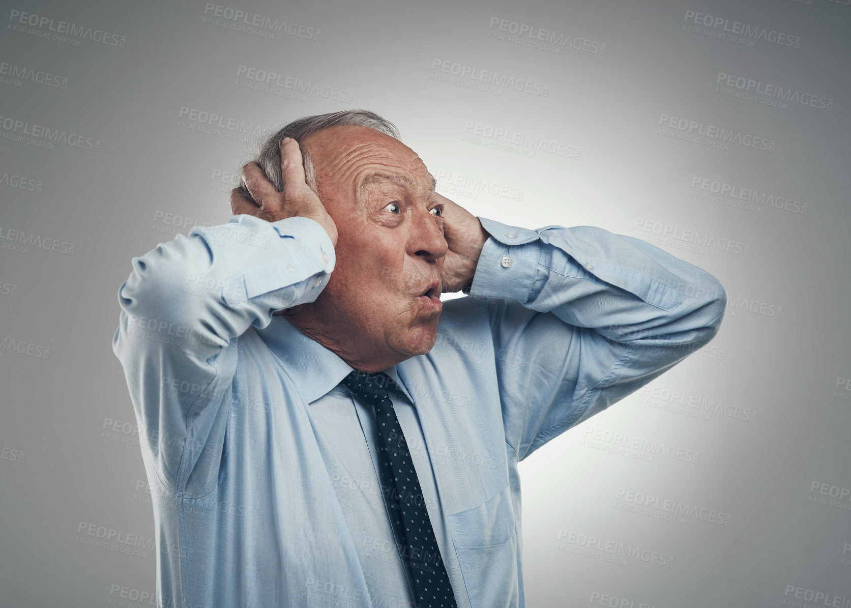 Buy stock photo Shot of a senior businessman standing against a grey studio background with his head in his hands and looking shocked