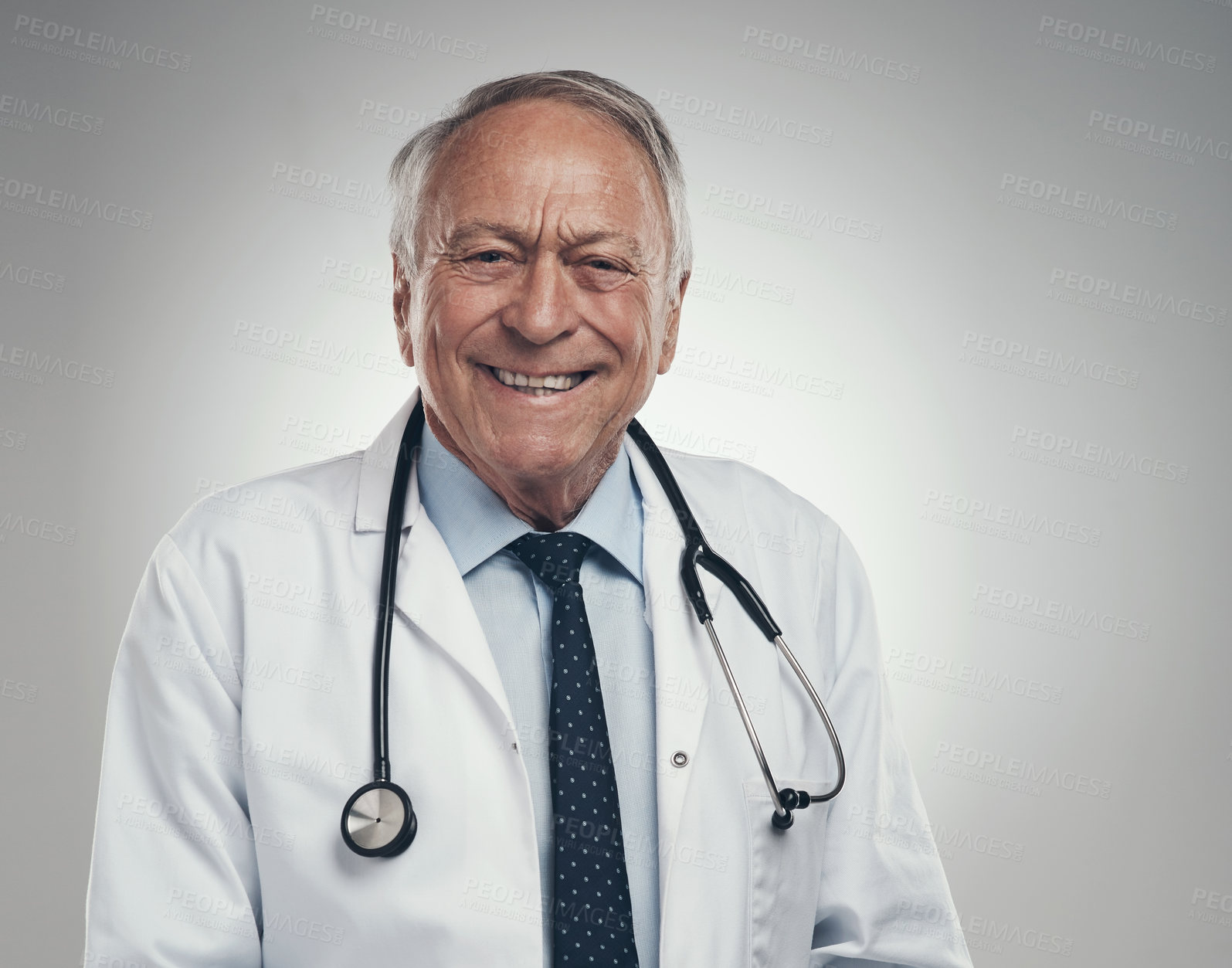 Buy stock photo Shot of a happy elderly male doctor in the studio against a grey background