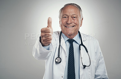 Buy stock photo Shot of an elderly male doctor in a studio giving a thumbs up against a grey background