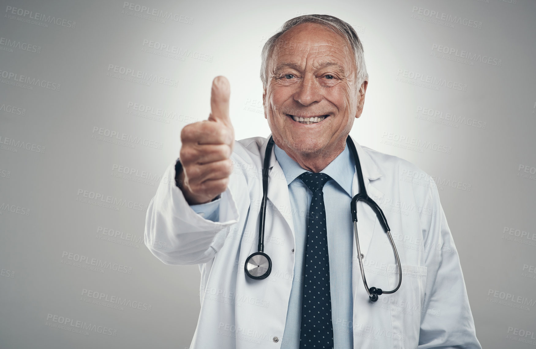 Buy stock photo Shot of an elderly male doctor in a studio giving a thumbs up against a grey background