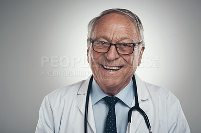 Buy stock photo Shot of a happy elderly male doctor in the studio against a grey background