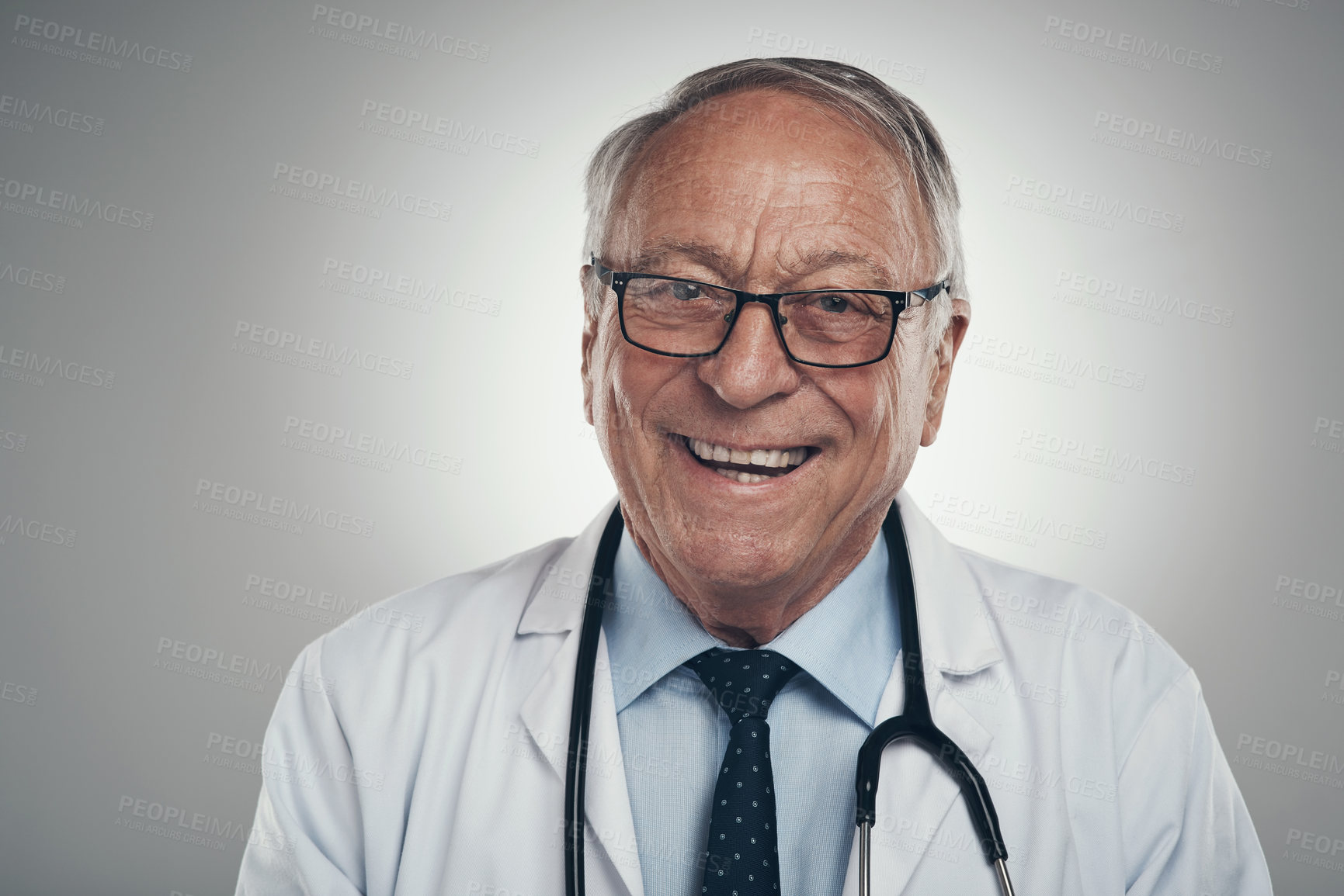 Buy stock photo Shot of a happy elderly male doctor in the studio against a grey background