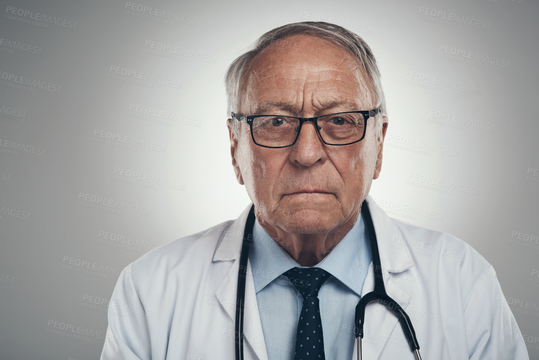 Buy stock photo Shot of an elderly male doctor in a studio against a grey background