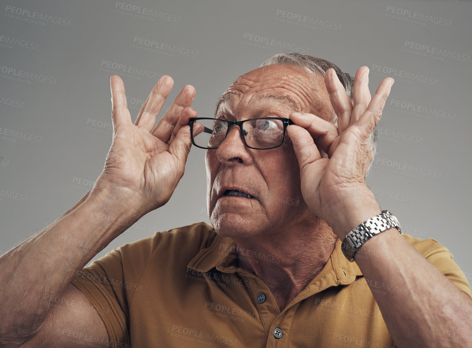 Buy stock photo Studio shot of an elderly man adjusting his spectacles against a grey background