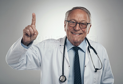 Buy stock photo Shot of an elderly male doctor holding his finger up in a studio against a grey background