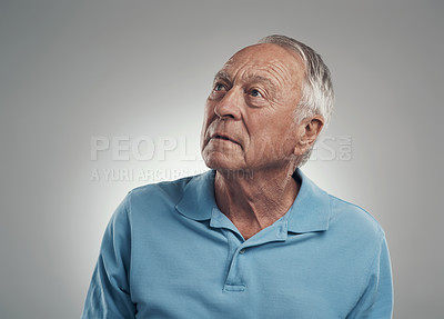 Buy stock photo Shot of an older man looking off into the distance in a studio against a grey background