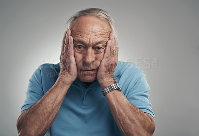 Buy stock photo Shot of an elderly man clasping his hands to his face in a studio against a grey background