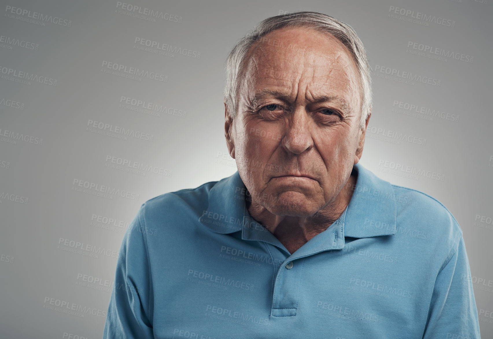 Buy stock photo Shot of an old man looking angrily at the camera in a studio against a grey background