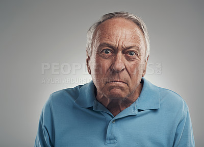 Buy stock photo Shot of an old man looking angrily at the camera in a studio against a grey background