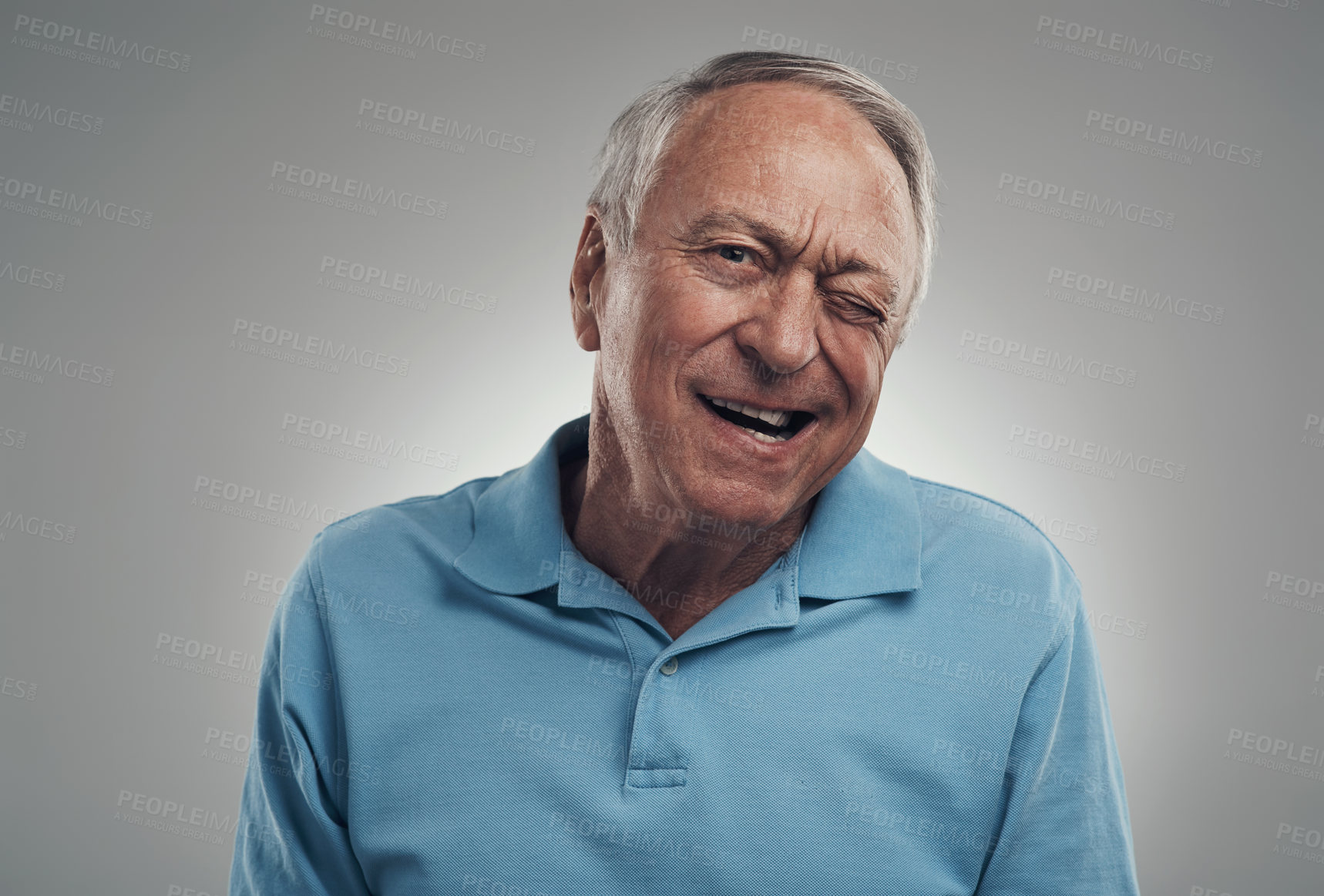 Buy stock photo Shot of a older man winking at the camera in a studio against a grey background